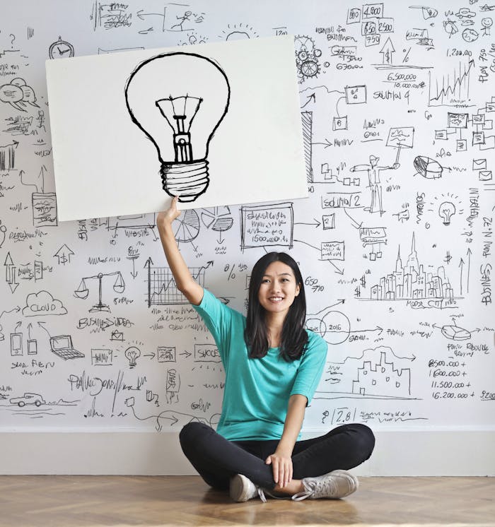 Services Young woman holds a light bulb drawing against a creative brainstorming wall.